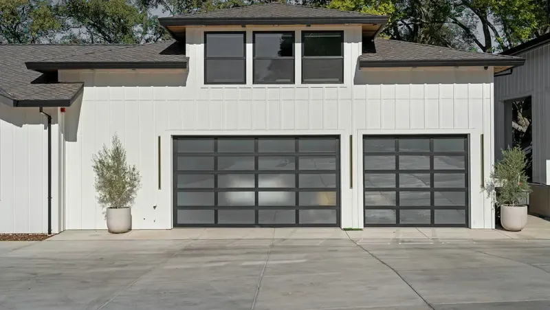 Two black framed glass garage doors on a white house
