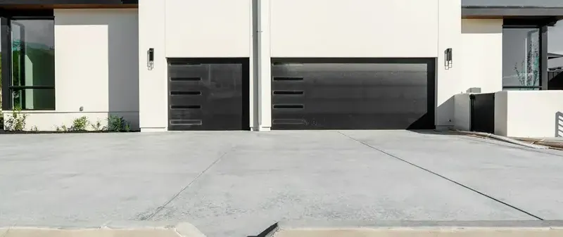 Two dark steel garage doors on a modern white house