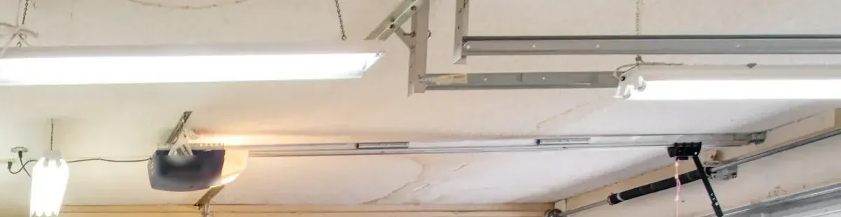 A garage door opener and its rail on a garage ceiling